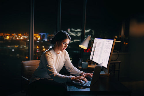 Professional woman working late at night on project in office
