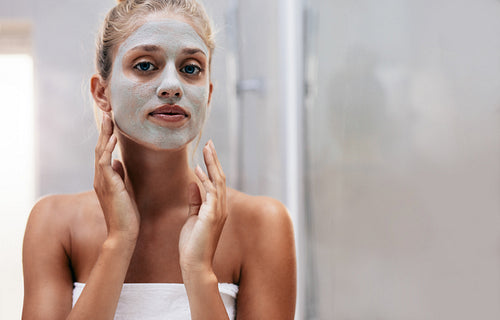 Woman with facial mask in bathroom