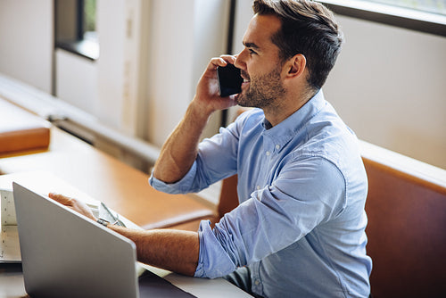 Businessman at desk talking on cell phone