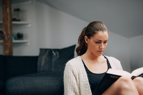 Young woman reading a book at home