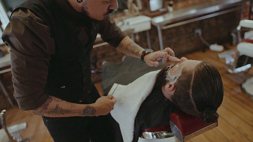 Hairdresser grooming beard of client