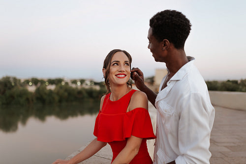 Lovers smiling at each other while standing on a bridge
