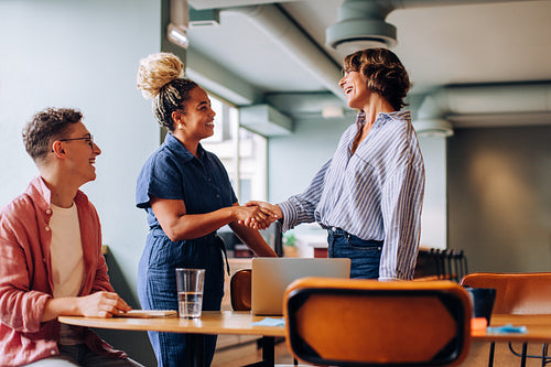 Two women greeting each other and exchanging smiles during a casual meeting
