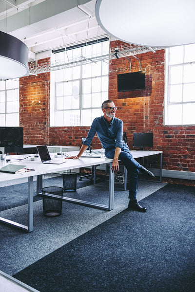 Happy mature businessman sitting on an office desk