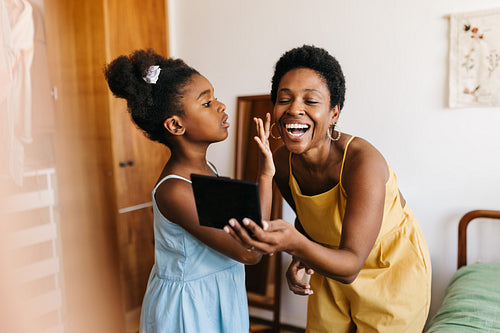 Stylish little girl applying her mom's makeup using a makeup palette