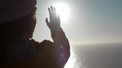 Woman looks at the sun through her hand