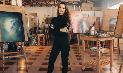 Professional painter standing in her atelier with her arms cross