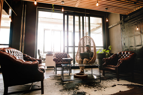 Young man relaxing in office lounge with laptop