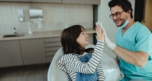 Dentist and child high five after successful dental checkup
