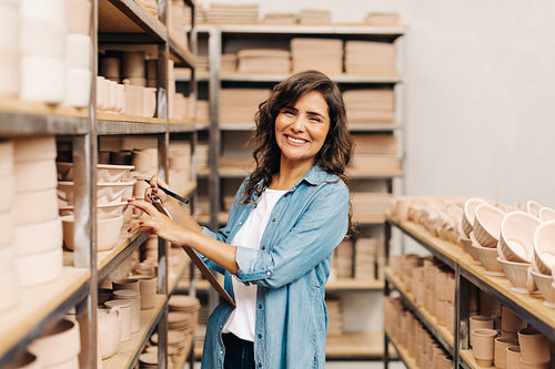 Cheerful ceramist smiling at the camera in her shop