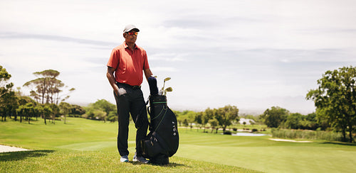 Sportsman standing on a golf course with a golf bag full of clubs