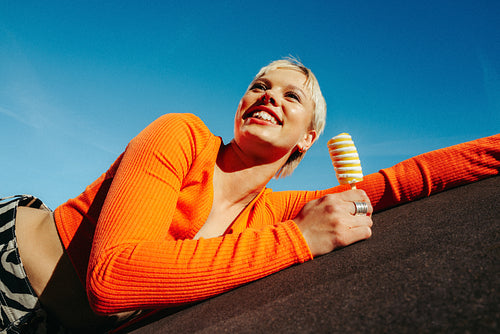 Cheerful woman enjoys popsicle in vibrant summer colors outdoors