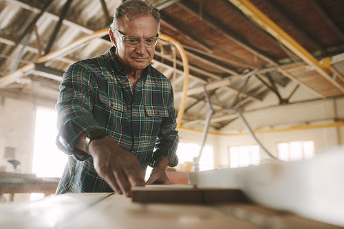 Carpenter cutting wood planks in electric saw