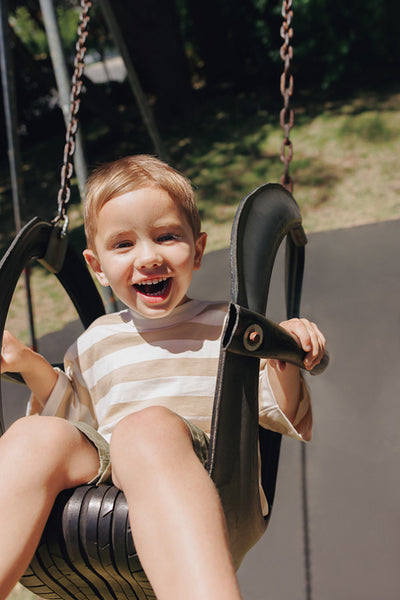 Smiling child swinging outdoors on a sunny day in the park