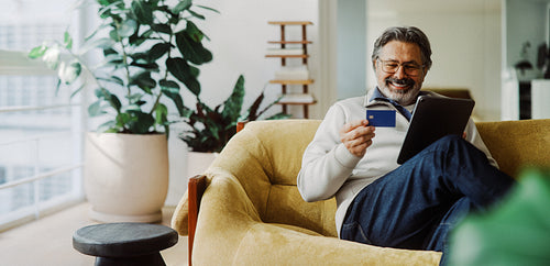 Senior man shops online with tablet and credit card