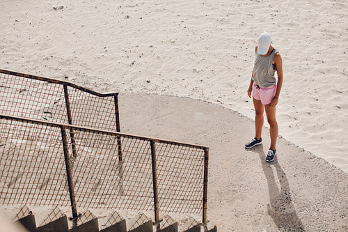 Young woman standing by a staircase at the beach