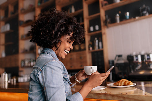 African woman cafe using mobile phone and smiling