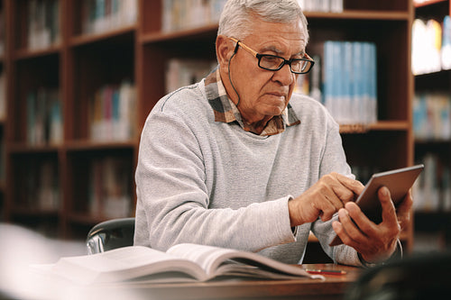 Senior man reading in a library