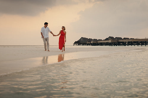 Retired couple enjoying a luxury vacation walking on a beach at sunset
