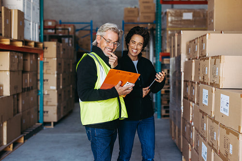 Happy warehouse managers smiling while looking at a clipboard