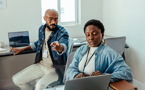 Manager and colleagues in a business meeting discussing project details in a modern office