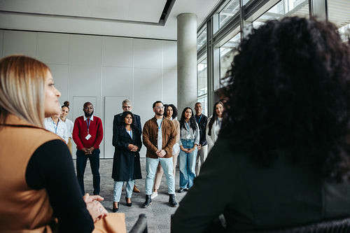 Business people attending a seminar with a diverse group standing in an office space