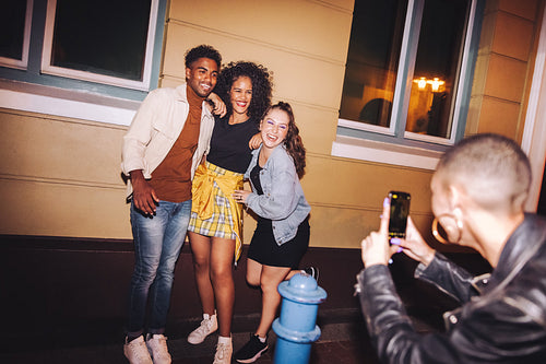 Friends posing for a group photo in front of a camera phone