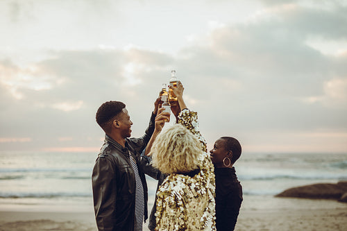 Friends celebrating with beers at beach