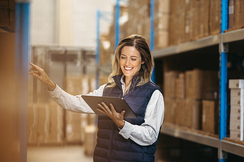 Happy logistics manager doing stock control using a digital tablet