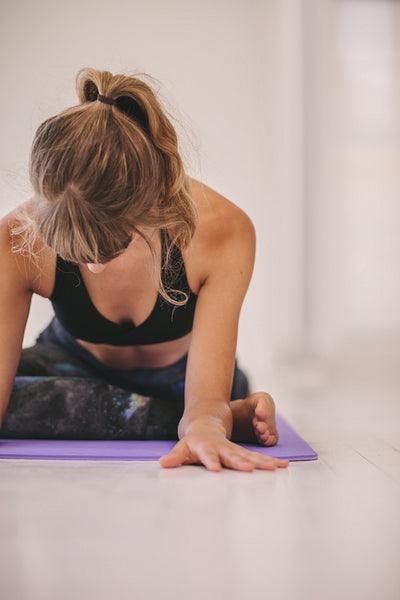 Woman doing stretching exercise on yoga mat