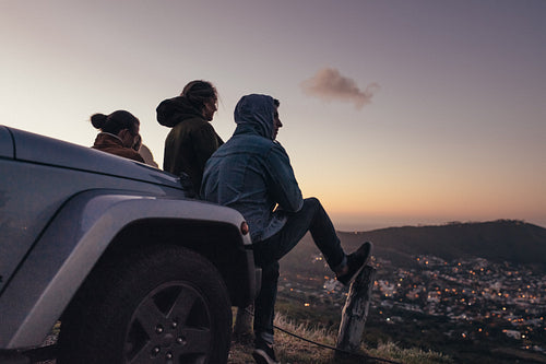 Friends sitting on a hilltop looking at the city below