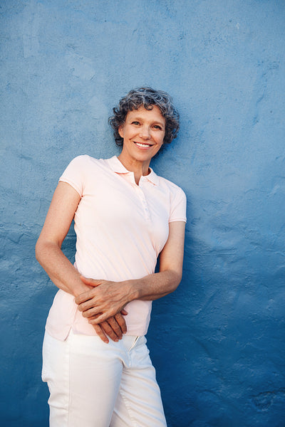 Relaxed mature lady leaning to a wall