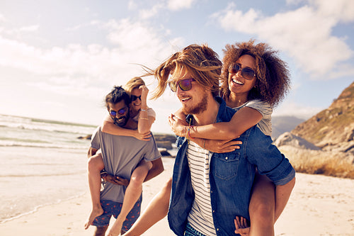 Young couple playing piggyback on beach