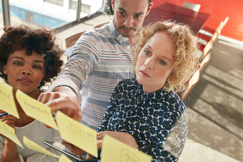Coworkers looking over a postit note wall and brainstorming