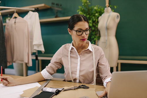 Creative fashion designer using laptop in her studio