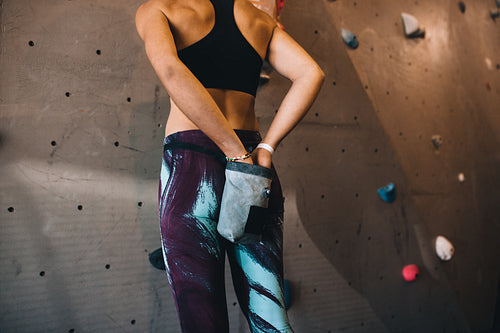Woman wall climber coating hands with gripping powder