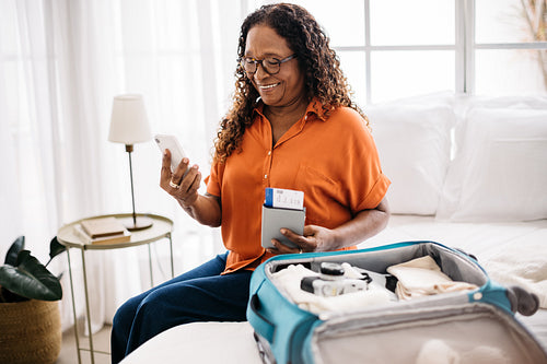 Retirement travel: Mature woman making arrangements for a hotel stay with her smartphone