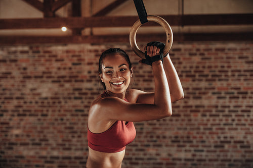 Fit woman holding gymnast rings at the gym