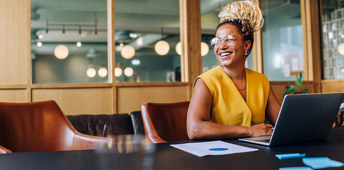 Confident professional woman smiling and working on a laptop in the office