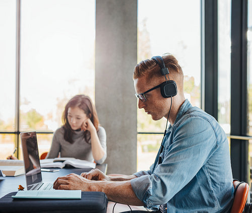 College students working on school assignment in library