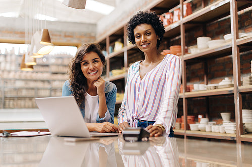 Cheerful female entrepreneurs smiling at the camera in their ceramic shop