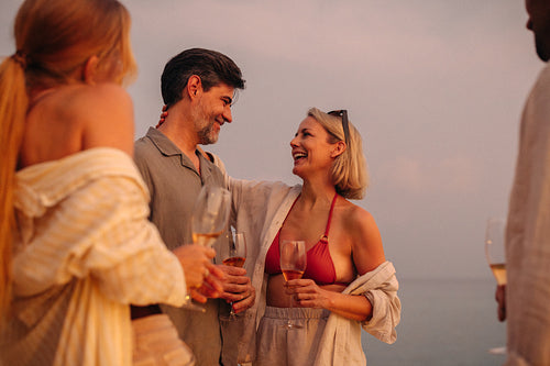 Parents showing affection while celebrating a holiday with friends on a beach