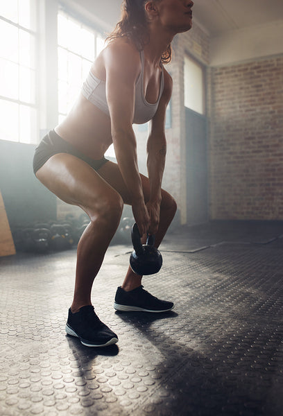 Muscular young woman exercising with kettlebell