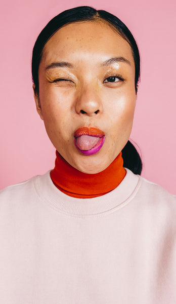Playful woman winking and sticking her tongue out in a studio