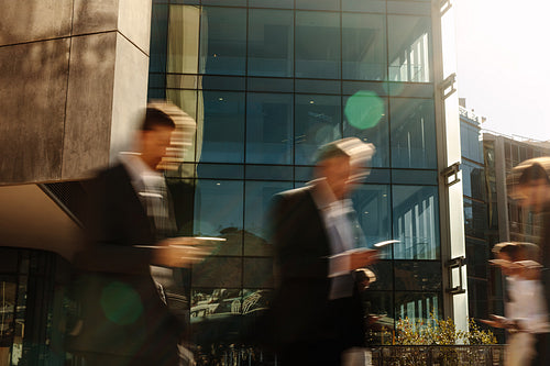 Business people using mobile phone while walking on street to office