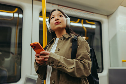 Commuter on subway checking phone while listening
