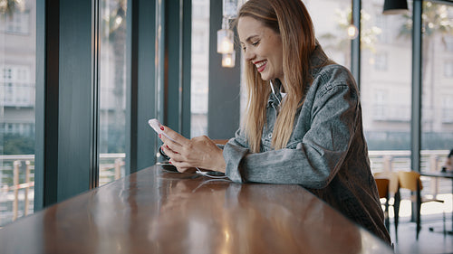 Woman at a cafe using mobile phone and smiling