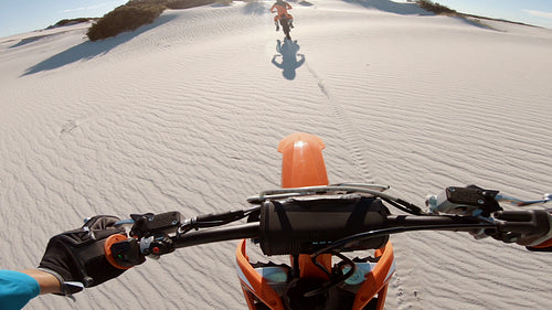 Motocross athlete riding behind his competitor in a desert