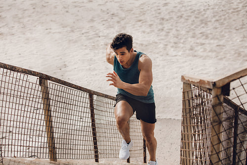 Fit young man running up the steps at beach