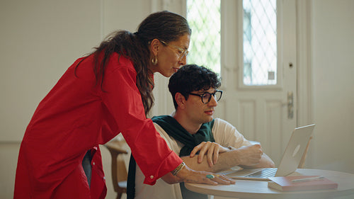 Woman mentors a man at a laptop during one-on-one training at work